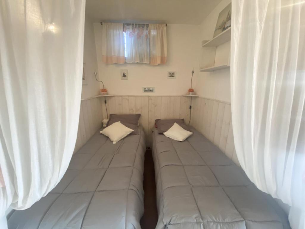 Cette chambre comprend 2 lits et des rideaux. dans l'établissement AS22947-Studio cabine résidence direct sur plage, au Grau-du-Roi