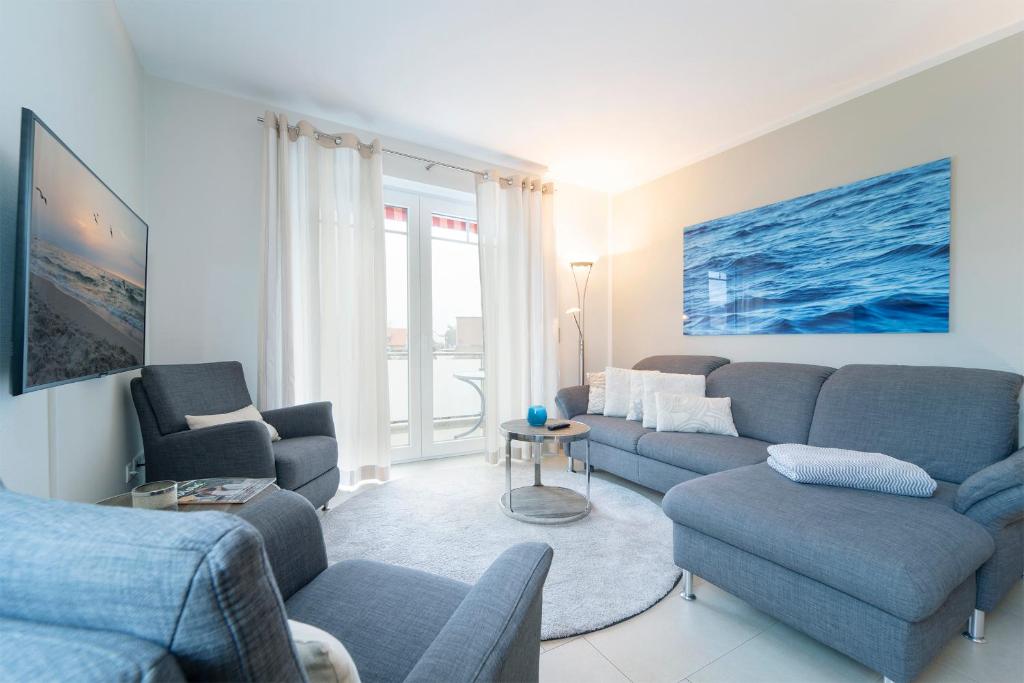 un soggiorno con divano blu e sedie di Blankwasserweg 57 Wohnung 5 a Grömitz