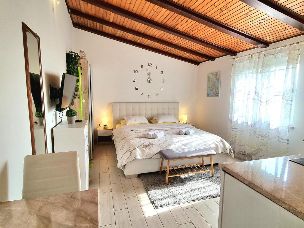 een slaapkamer met een bed en een klok aan de muur bij Studio Apartment Lino in Skrbčići