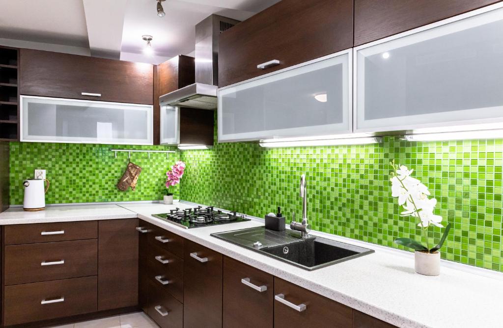 a kitchen with a sink and a green tiled wall at ClickTheFlat Piękna Center Apart Rooms in Warsaw