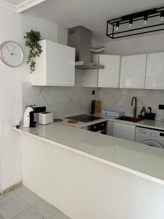 a kitchen with white cabinets and a clock on the wall at Apartament La Mata in La Mata