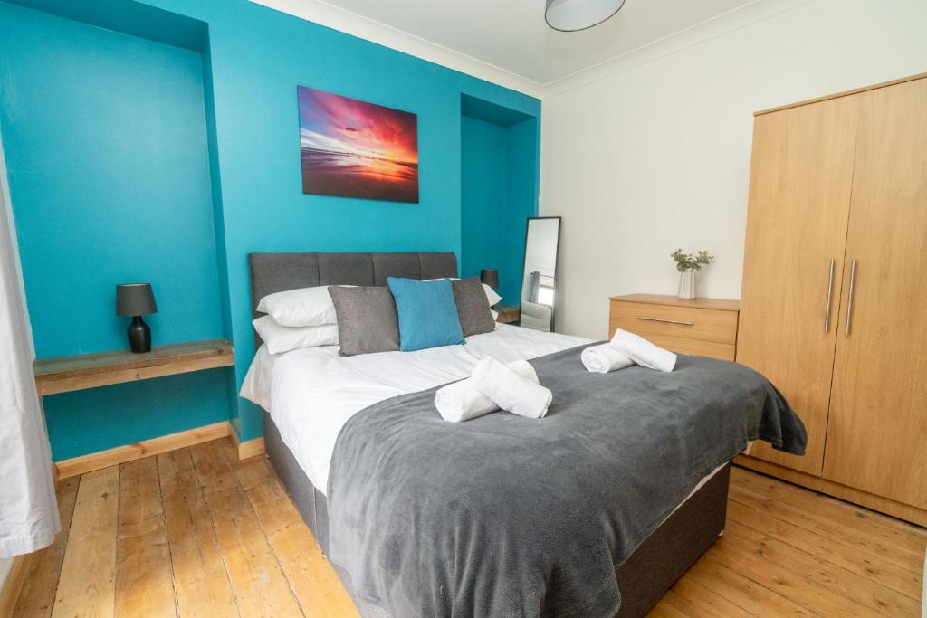 um quarto com uma cama e uma parede azul em Business friendly & Spacious 2BR home - Perfectly located for working in Swansea em Swansea