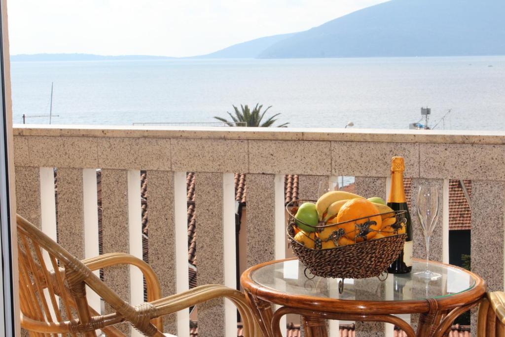 a table with a basket of fruit and a bottle of champagne at Tazex Apartments in Herceg-Novi