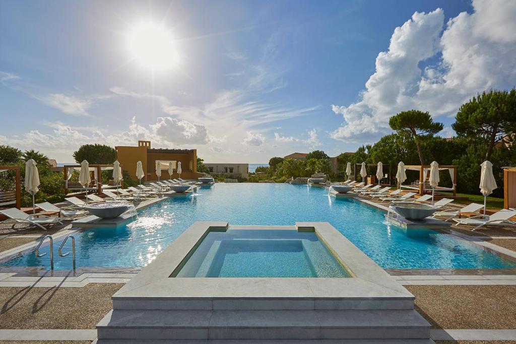a large swimming pool with lounge chairs and a swimming pool at The Westin Resort, Costa Navarino in Romanu