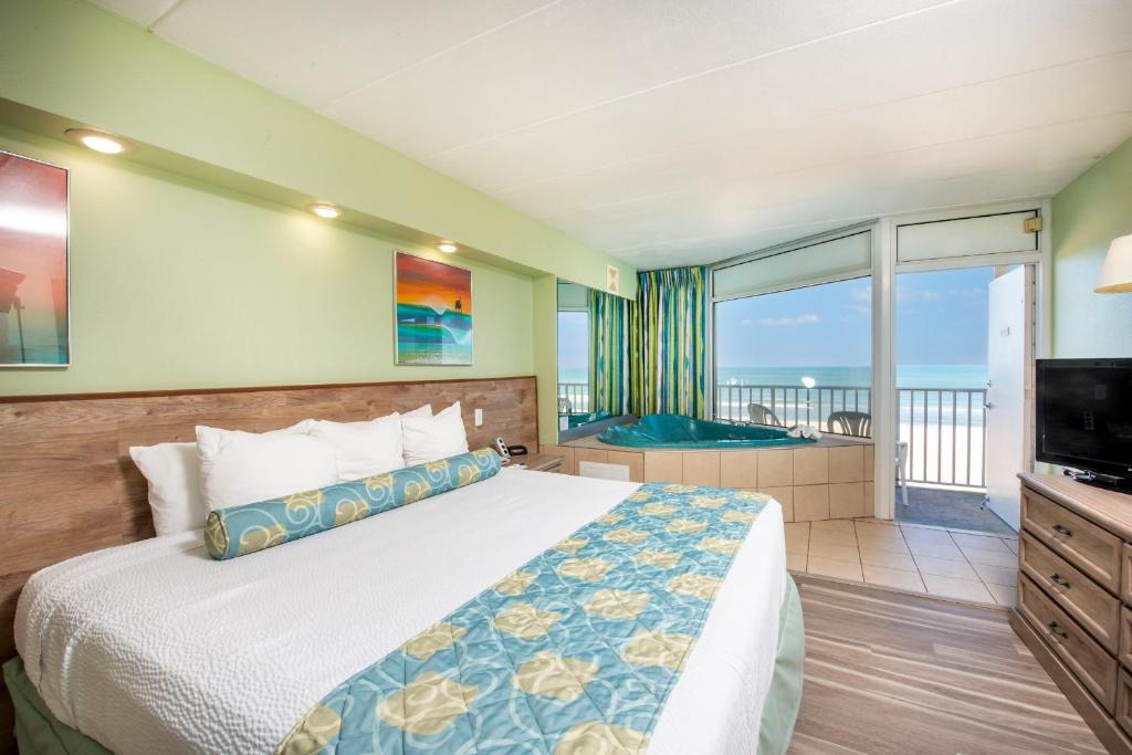 a bedroom with a bed and a television and a balcony at The Schooner Inn in Virginia Beach