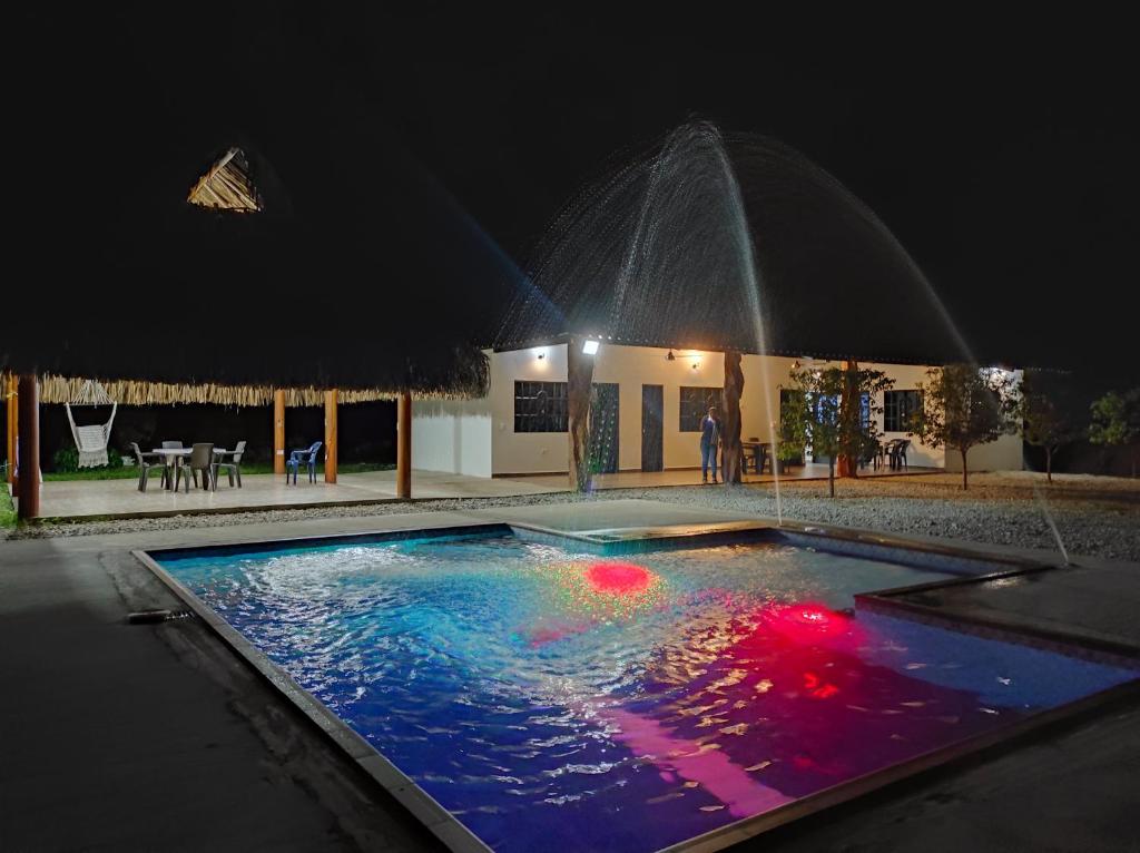 ein Schwimmbad in der Nacht mit einem Springbrunnen in der Unterkunft Parcela el paraiso in Doradal