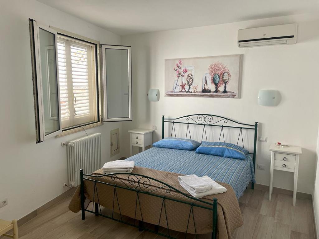 a bedroom with a bed with blue pillows and a window at Mimi Leuca B&b in Leuca