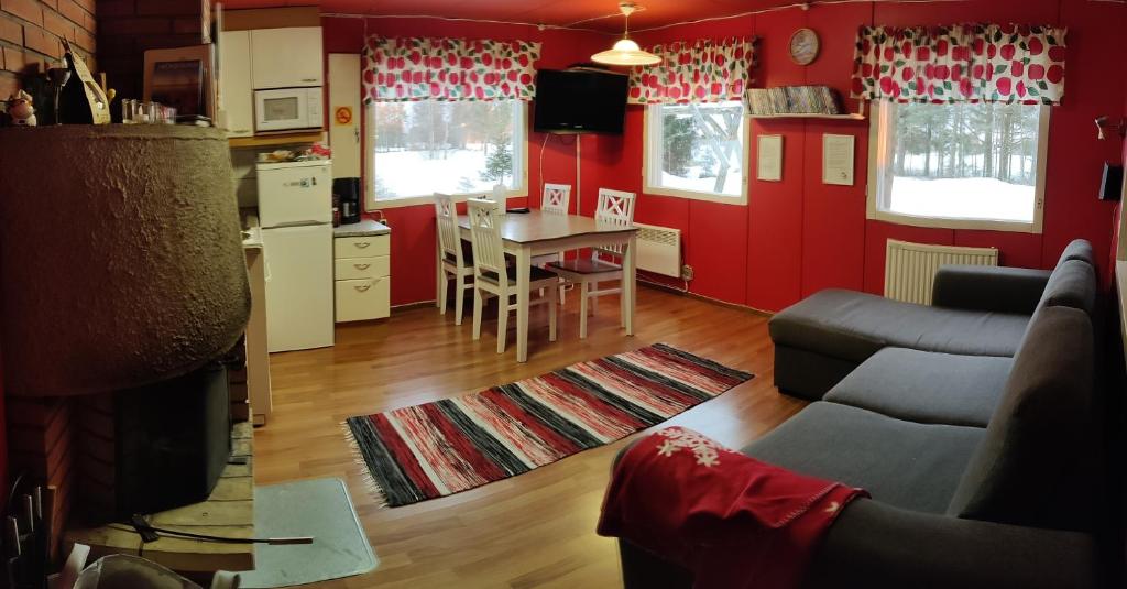 a living room with red walls and a table and a couch at Punainen tupa in Kalajoki