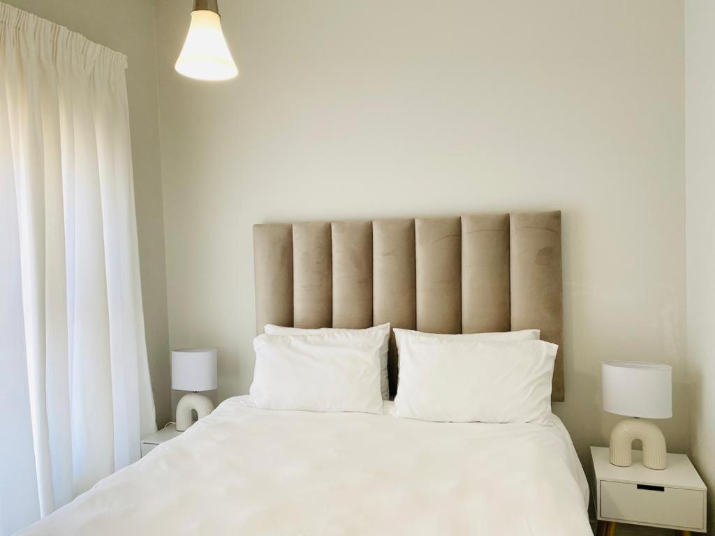 1 dormitorio con 1 cama blanca grande con almohadas blancas en Greencreek Beautifully furnished apartment, en Pretoria
