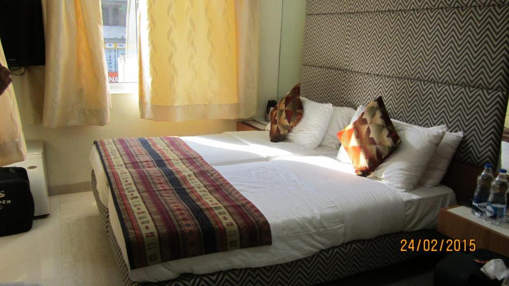 a bedroom with a bed with white sheets and pillows at Empire Hotel - Grant Road in Mumbai