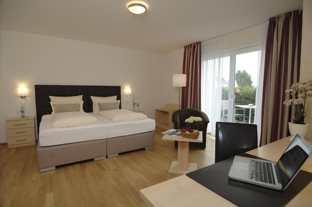 Schlafzimmer mit einem Bett und einem Schreibtisch mit einem Laptop in der Unterkunft Hotel-Restaurant Sebastianushof in Bonn