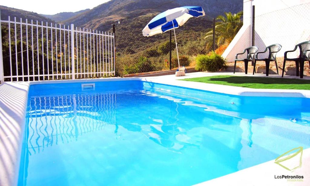 una piscina azul con sombrilla y sillas en Cortijo Los Petronilos, en Las Lagunillas