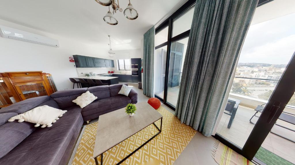 - un salon avec un canapé violet et une grande fenêtre dans l'établissement St Julians Central luxury apartment, à San Ġiljan