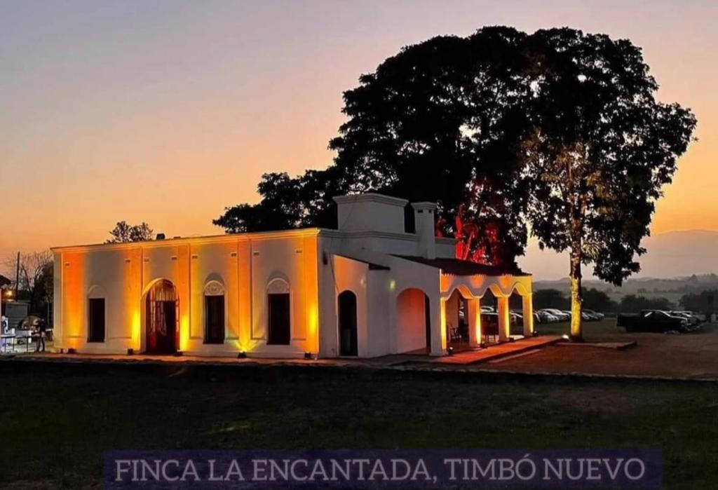 un edificio bianco con un albero di fronte di CASA QUINTA LA ENCANTADA a San Miguel de Tucumán