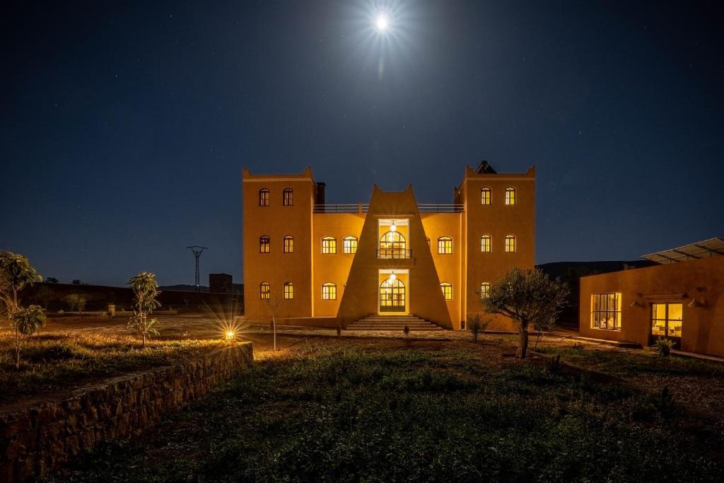 a large building at night with the moon above it at Le Domaine M in Ouzoud