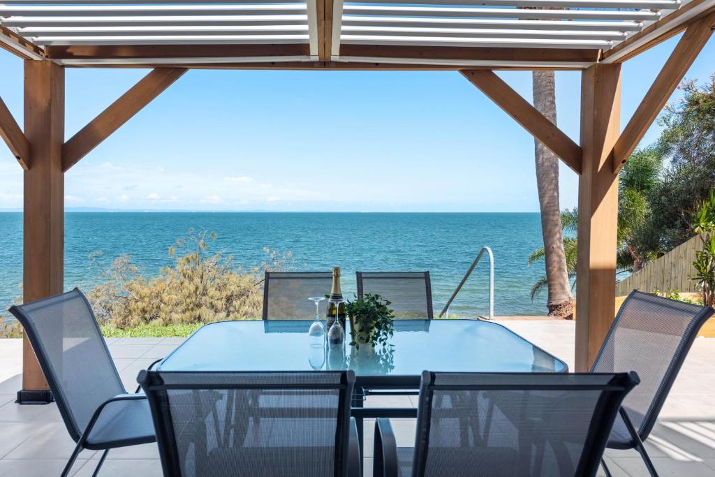 een eettafel met stoelen en uitzicht op de oceaan bij Sea Breeze Two Bedroom Apartment in Redcliffe