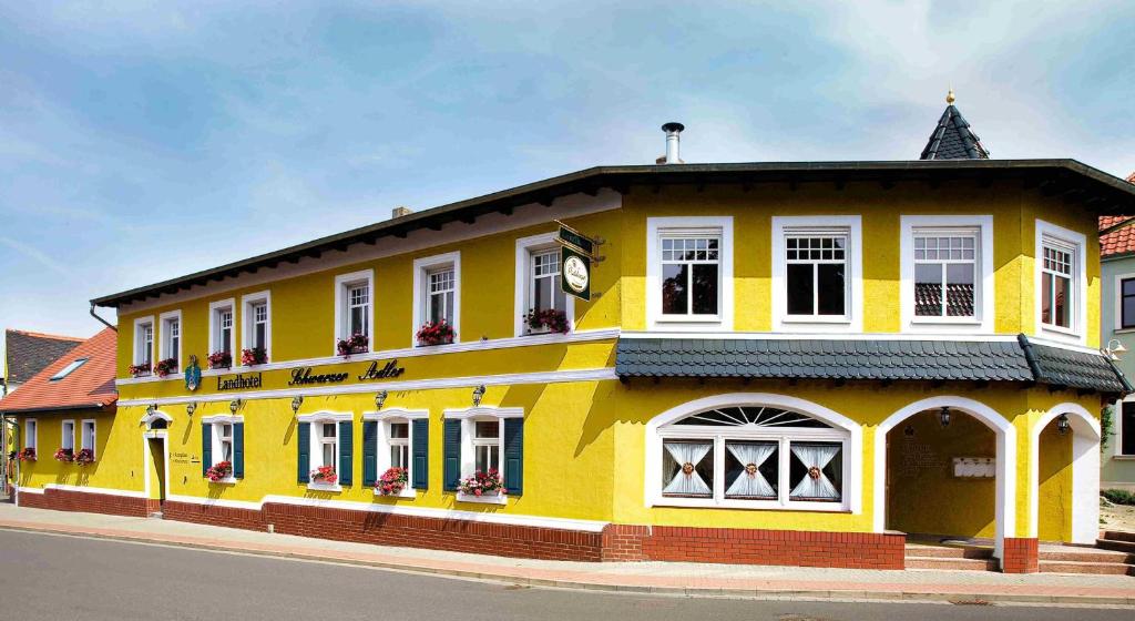 un bâtiment jaune sur le côté d'une rue dans l'établissement Landhotel Schwarzer Adler, à Sülzetal