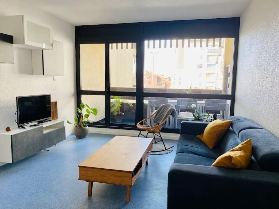 a living room with a blue couch and a table at Appartement 4 pers max à Seignosse le Penon in Seignosse