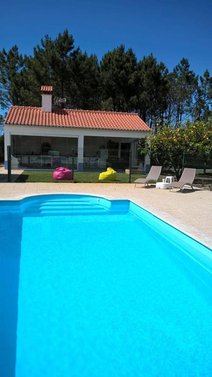 a large blue swimming pool in front of a house at Casa da Samouqueira in Rogil