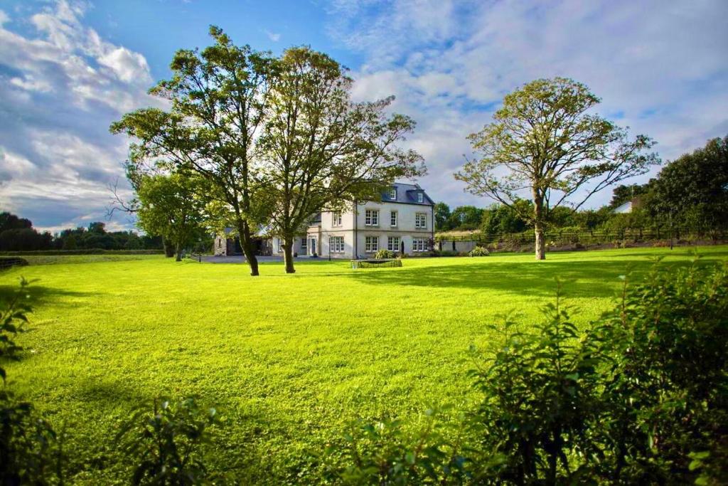 un grande prato con una casa bianca e alberi di Bailey's Court, Guest Accommodation a Portadown