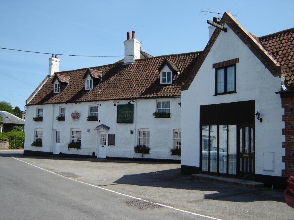 - un bâtiment blanc avec des fenêtres et des portes donnant sur une rue dans l'établissement The Crown Hotel, à Mundford