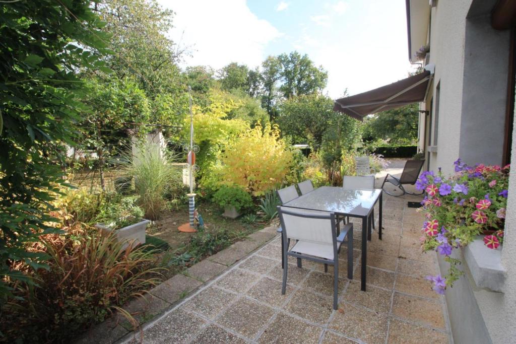 un patio con mesa y sillas en un jardín en Bel air, en Nexon