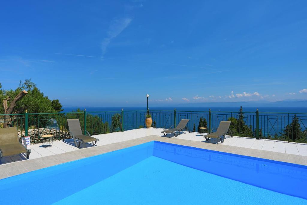 een zwembad met stoelen en de oceaan op de achtergrond bij Antigoni Villas in Longós