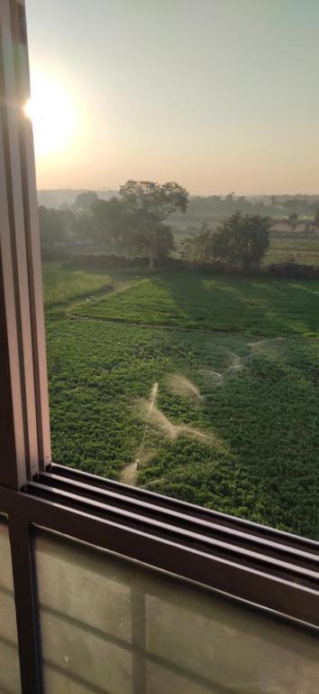 a window with a view of a green field at Love & Peace Apartment in Jabalpur