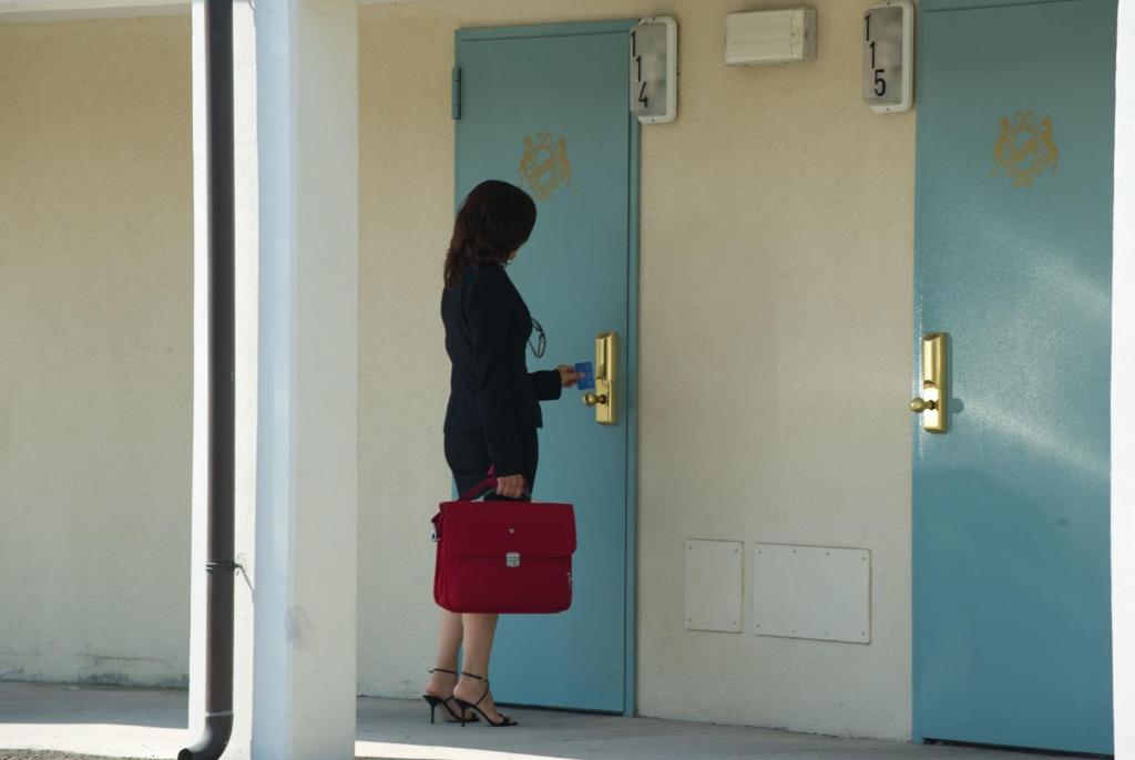 ラヴェンナにあるAutohotel Ravennaの赤いスーツケースを戸の前に持つ女