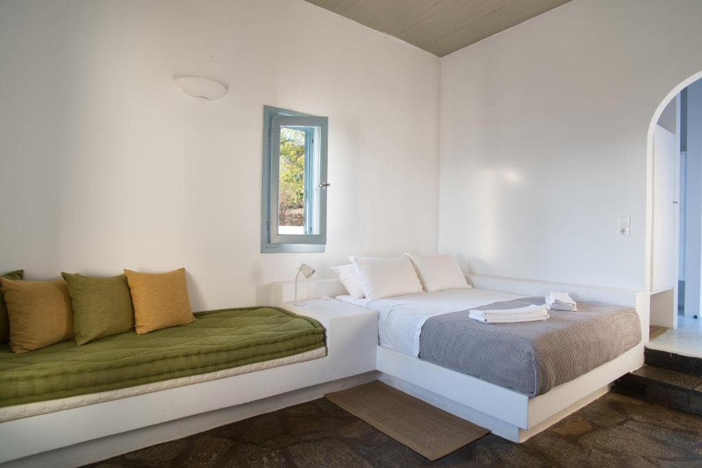 a white bedroom with a bed and a window at Oliaros seaside complex in Agios Georgios