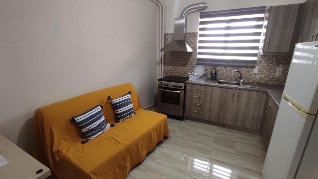a small kitchen with a yellow couch in a room at Cosy Apartment in relaxed neighbourhood in Amarynthos