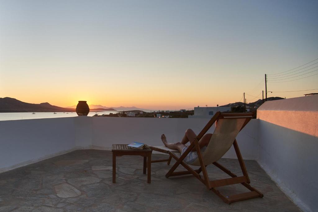 a chair on a balcony with the sunset in the background at Oliaros seaside complex in Agios Georgios