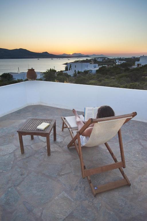 a child sitting in a chair reading a book at Oliaros seaside complex in Agios Georgios