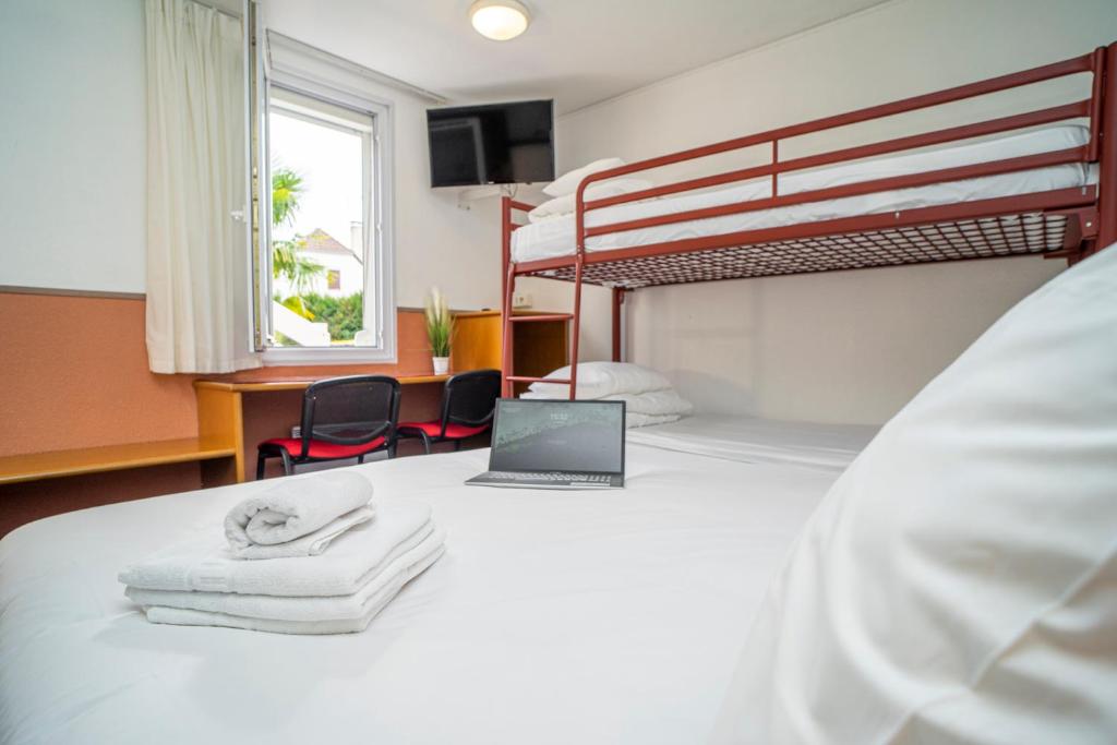 a bedroom with a bed with a laptop on it at Quick Palace Pau Zénith in Pau