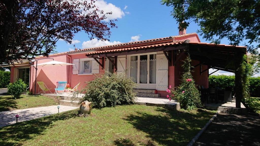 une maison rose avec une terrasse couverte et une cour dans l'établissement Gite De La Meronne, à Vindelle