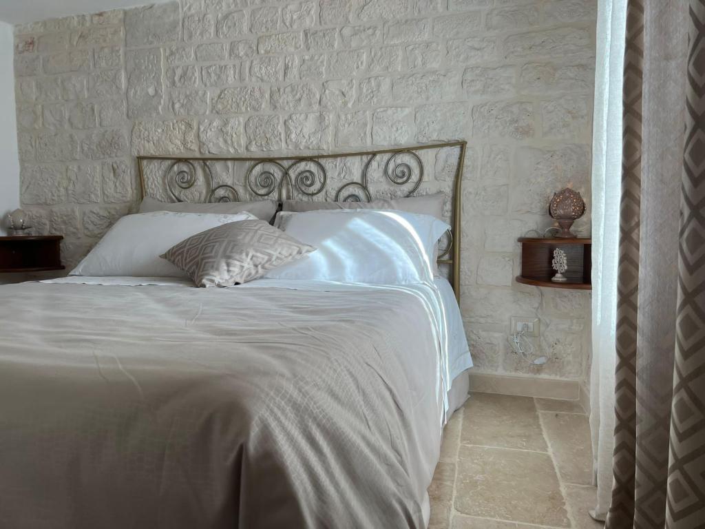 un letto con lenzuola e cuscini bianchi in una camera da letto di Cibum House ad Alberobello