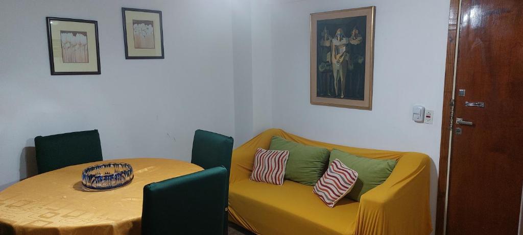 ein Tisch und ein gelbes Sofa mit Kissen drauf in der Unterkunft Manilo House in Mar del Plata