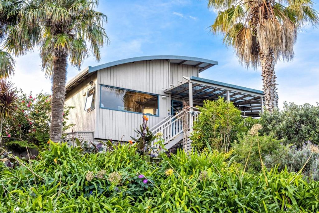 a house on a hill with palm trees at Oneroa Spa Retreat- Waiheke Escapes in Blackpool
