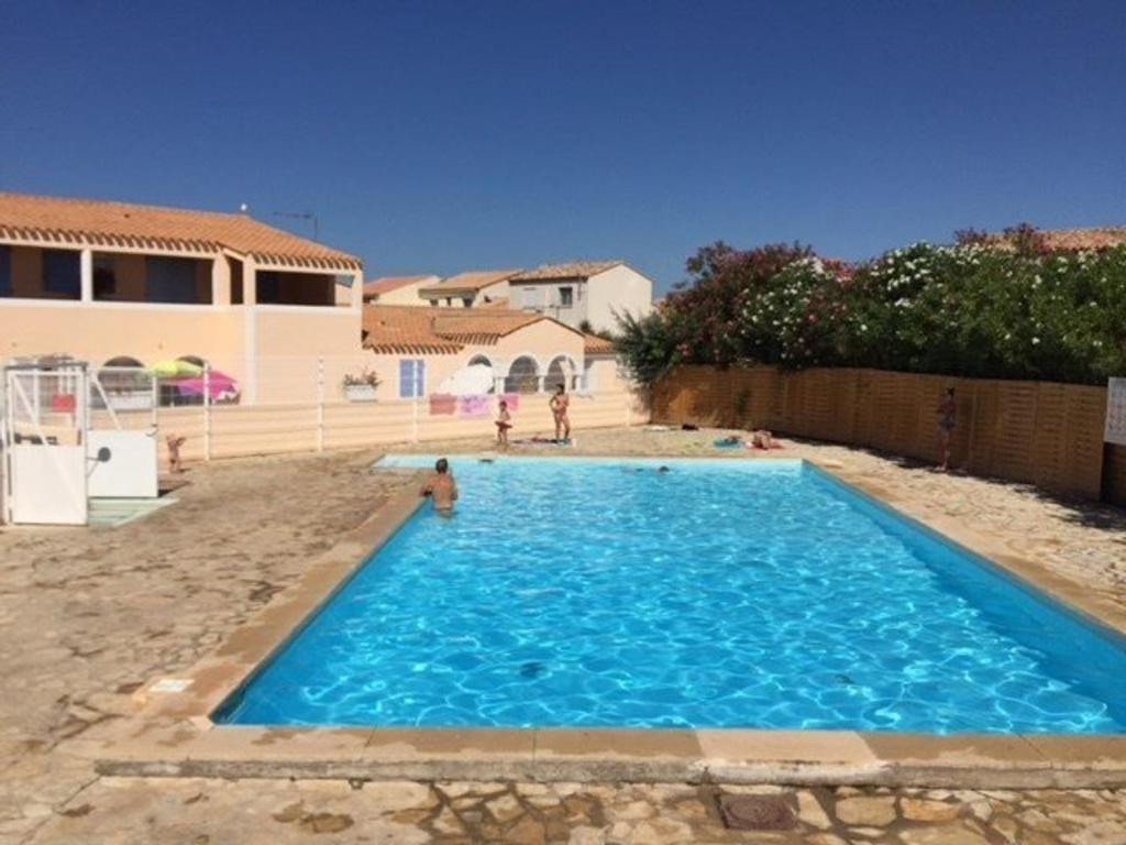 une grande piscine bleue devant une maison dans l'établissement Appartement T2 avec Piscine à 1.5 km de la Plage - 4 Couchages au Barcarès - FR-1-81-499, au Barcarès