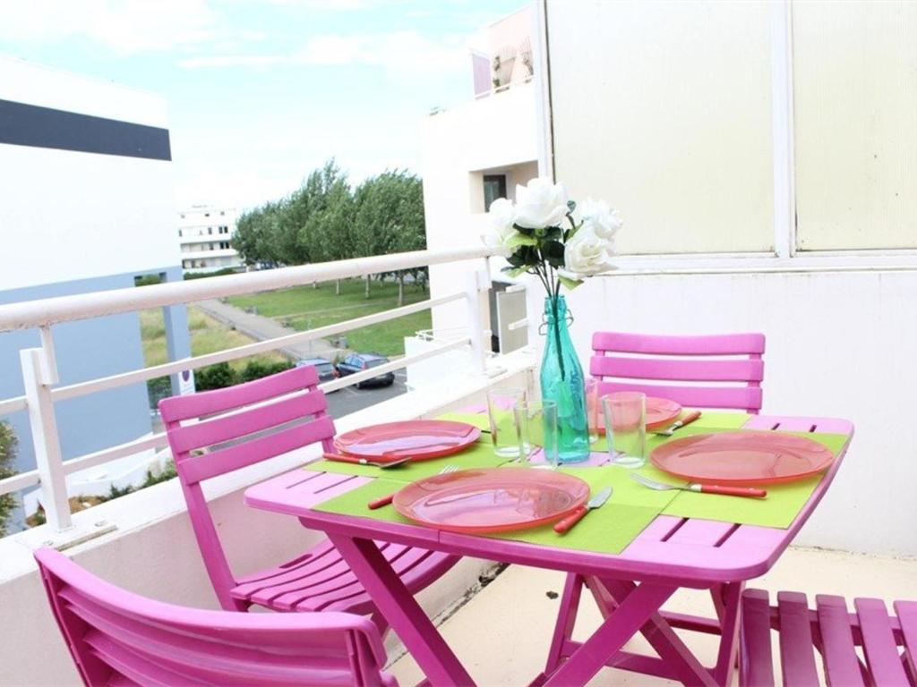 einen Tisch mit rosa Stühlen und eine Vase mit Blumen in der Unterkunft Appartement La Rochelle, 1 pièce, 4 personnes - FR-1-246-9 in La Rochelle