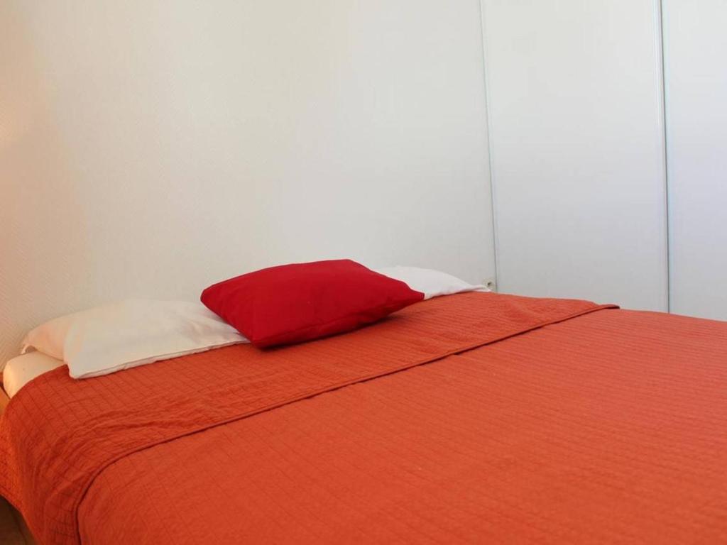 a red pillow sitting on top of a bed at Appartement La Rochelle, 2 pièces, 4 personnes - FR-1-246-286 in La Rochelle