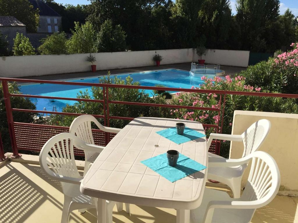 a white table and chairs on a balcony with a swimming pool at Appartement La Rochelle, 1 pièce, 2 personnes - FR-1-246-304 in La Rochelle