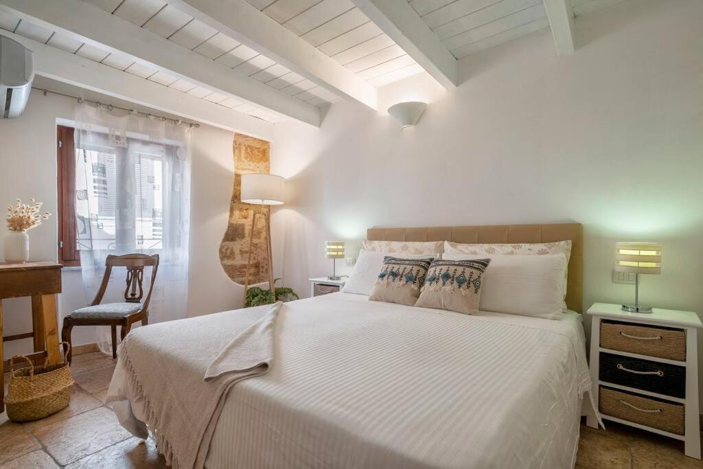 a bedroom with a large white bed and a desk at Little Flower in Alghero