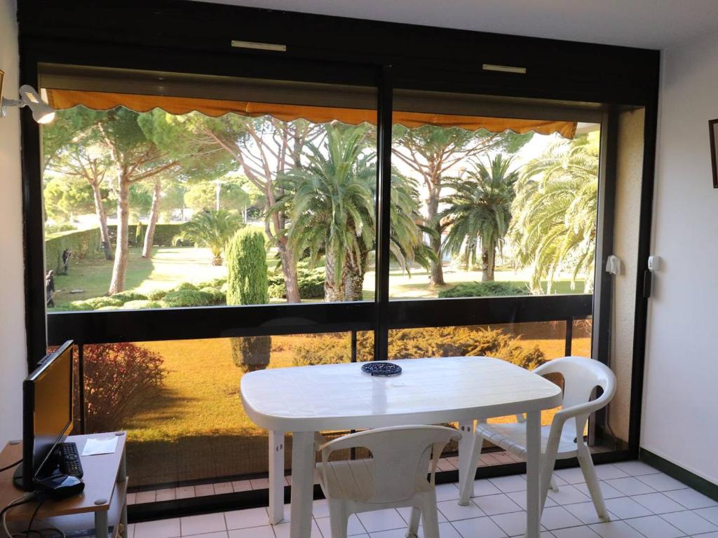 a white table and chairs in front of a large window at Studio Le Grau-du-Roi, 1 pièce, 4 personnes - FR-1-307-114 in Le Grau-du-Roi