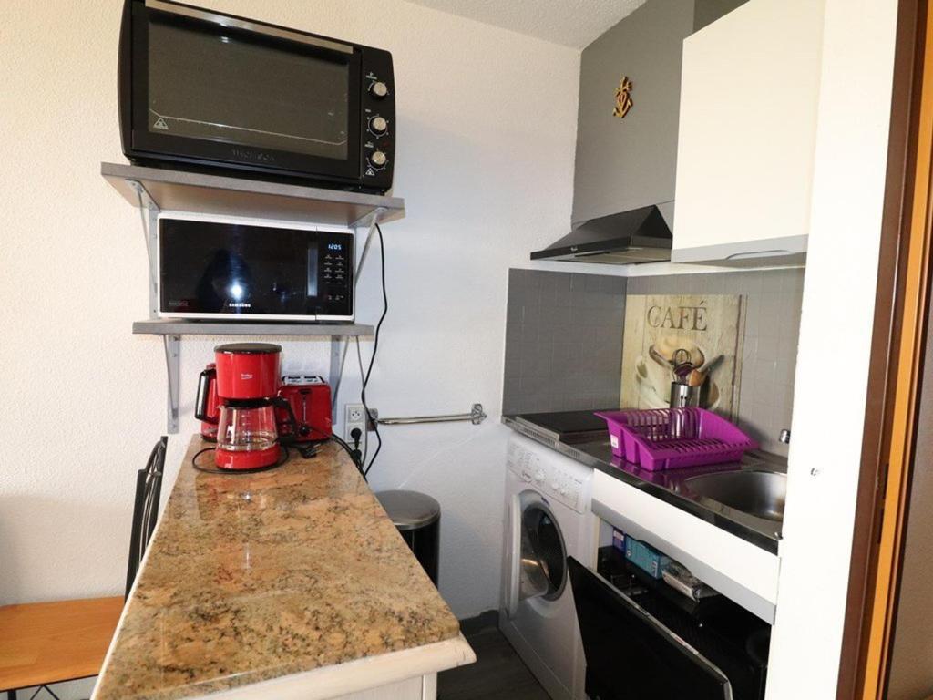 a small kitchen with a microwave and a sink at Studio Le Grau-du-Roi, 1 pièce, 4 personnes - FR-1-307-123 in Le Grau-du-Roi