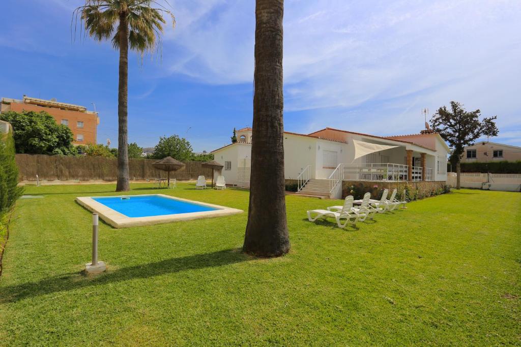einen Garten mit Pool und Palmen in der Unterkunft VILLA LUNA Beach Premium 9PAX in Torre de Benagalbón