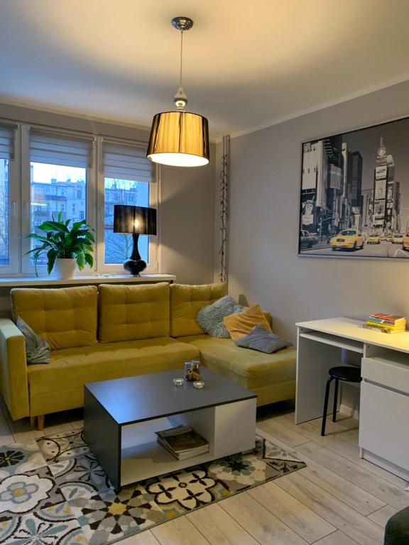 uma sala de estar com um sofá amarelo e uma mesa em W Muzycznej Dzielnicy em Bydgoszcz