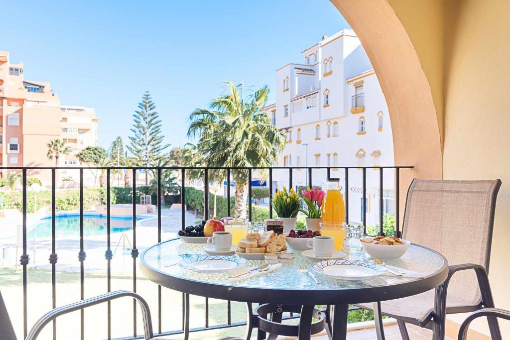einen Tisch mit Speisen auf einem Balkon mit Poolblick in der Unterkunft Casa Playa Bonita Primera linea de playa in Roquetas de Mar