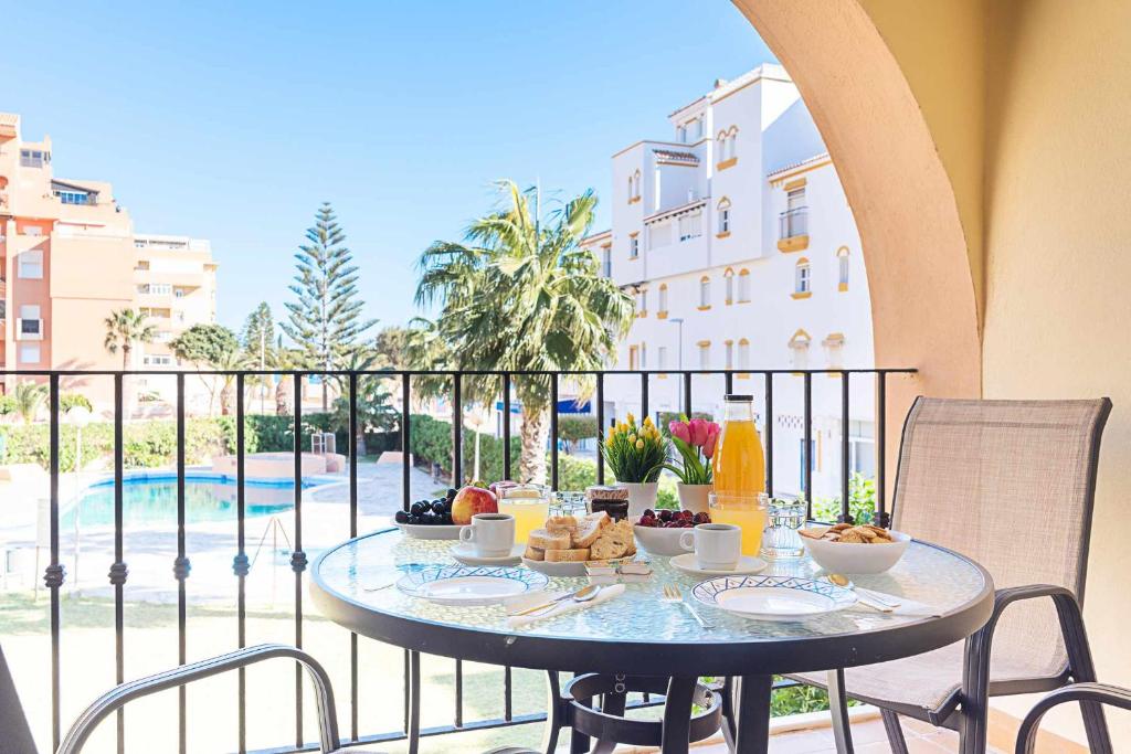 a table with food on a balcony with a view of a pool at Casa Playa Bonita Primera linea de playa in Roquetas de Mar
