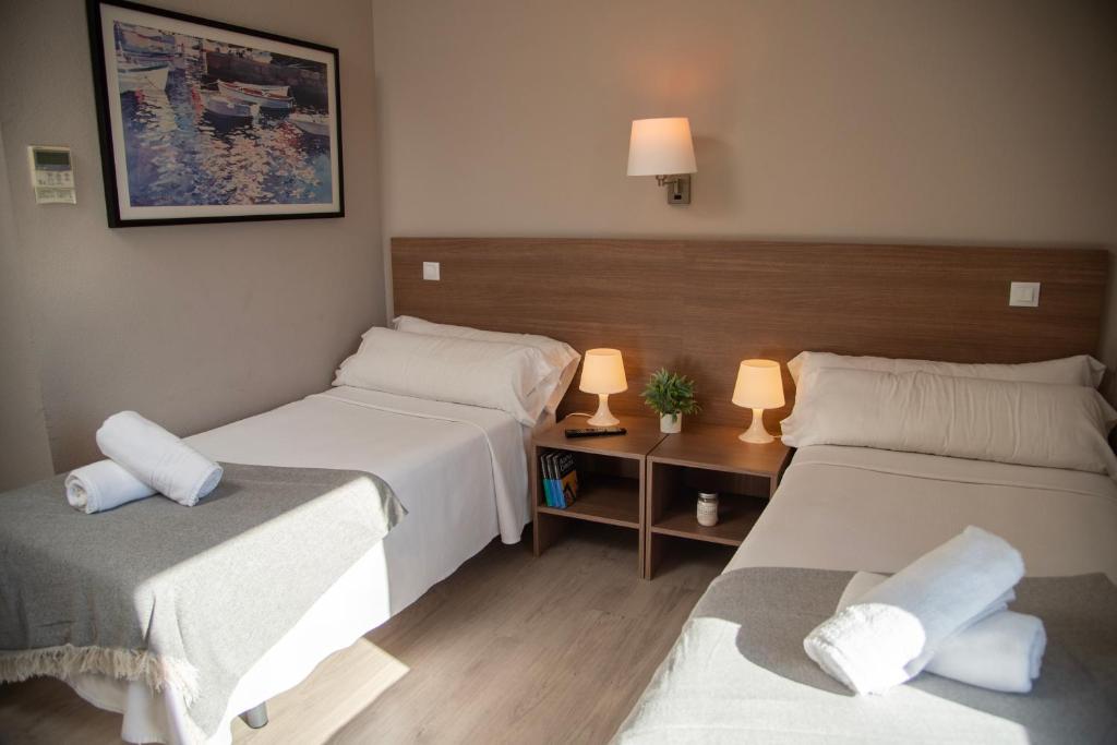 Habitación con 2 camas y mesa con 2 lámparas en Hotel La Parada, en Getafe